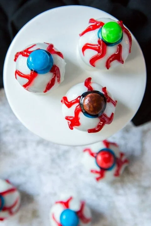 White eyeball truffles with red icing veins and M&M pupils on a white plate (RecipeGirl)