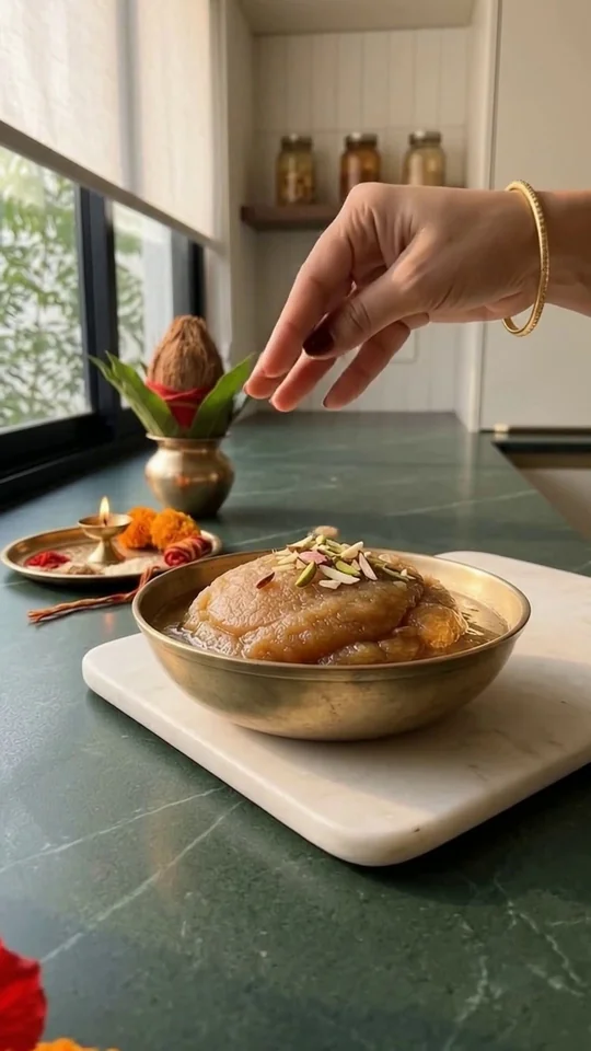 Singhara halwa topped with sliced almonds and pistachios in a brass bowl, beside a puja thali
